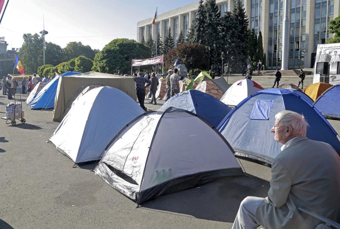 A man sits in front of the tents set by protesters after an anti-government rall