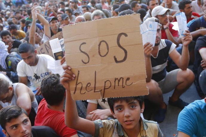 Un menor refugiado con una mensaje de 'SOS' en Budapest