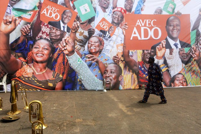 Un hombre camina delante de carteles de Alassane Ouattara