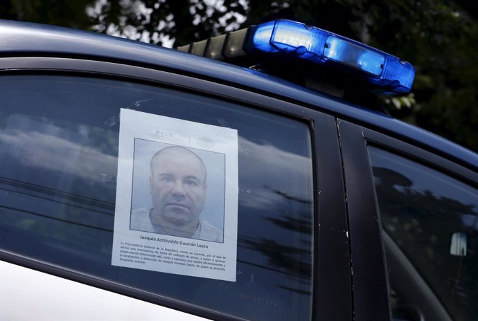 A police vehicle is seen a poster with a photo of drug lord Joaquin "El Chapo" G