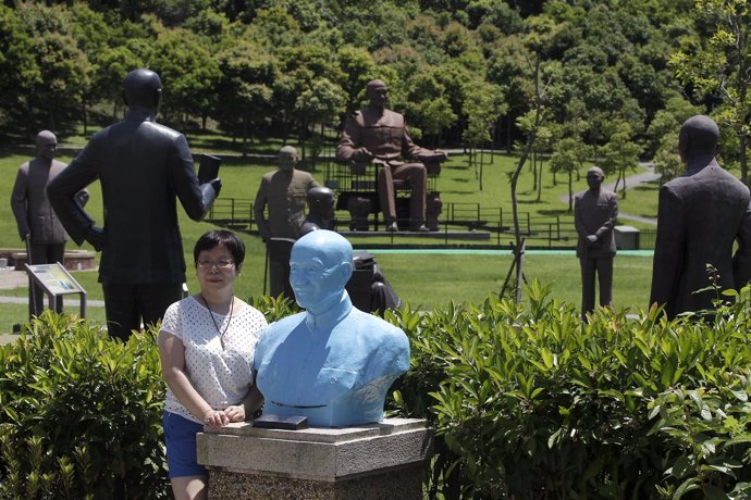 Una mujer posa para una foto junto a la estatua de expresidente de Taiwán