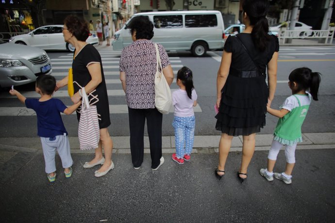 Tres mujeres chinas con niños de la mano