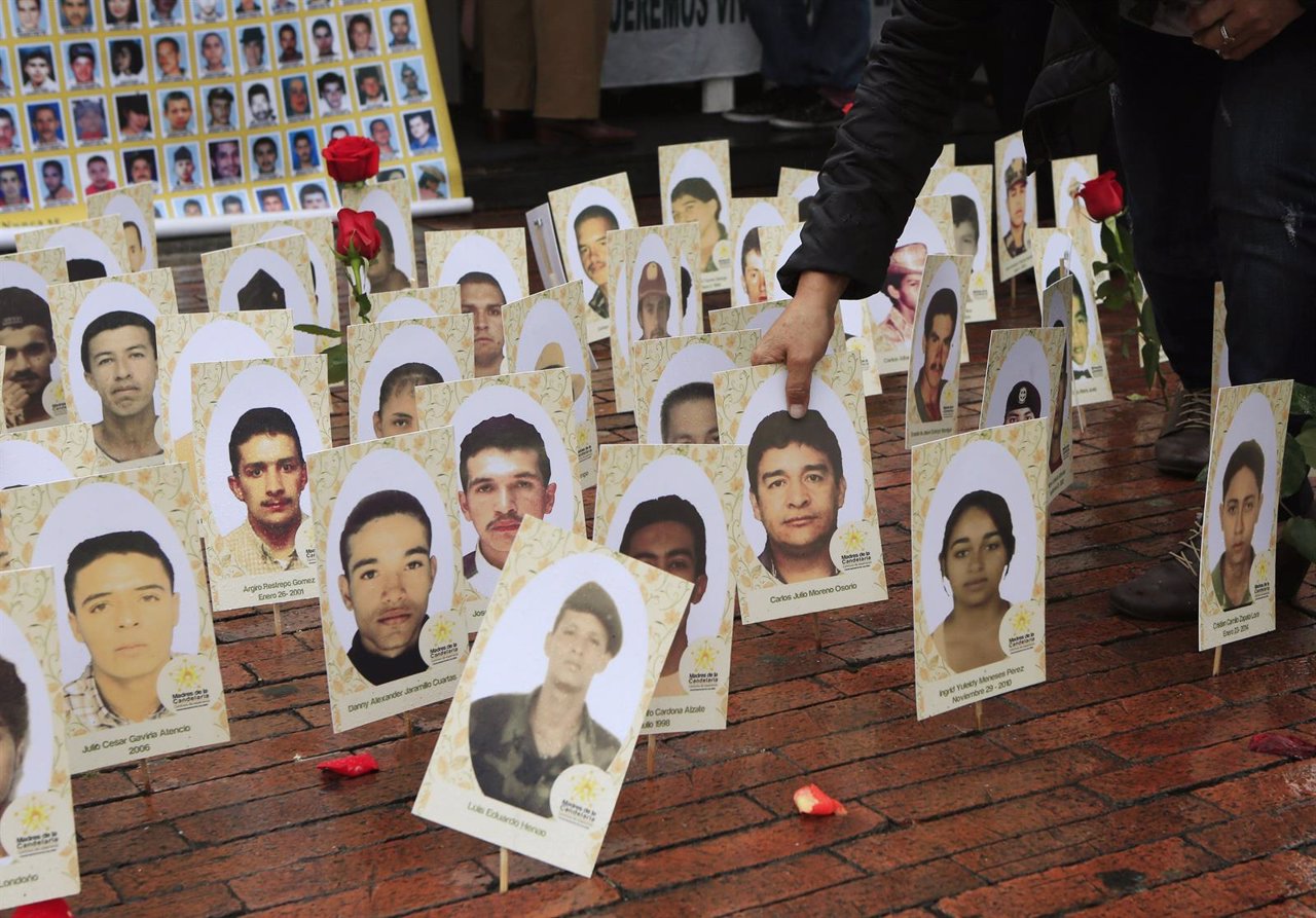 A woman locates a portrait among of a group of portraits of missing people durin