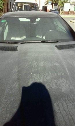 Particulas de cemento cubren el capó de un coche.