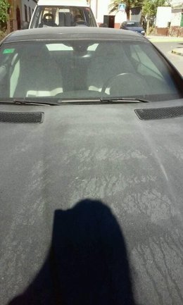 Particulas de cemento cubren el capó de un coche.