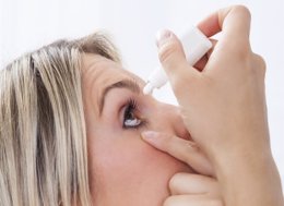 Chica con conjuntivitis echándose un colirio