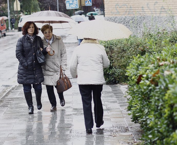 Gente bajos sus paraguas pasean por la calle.