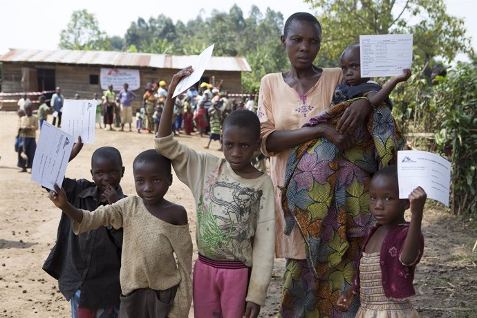 Una mujer y varios niños posan con sus certificados tras recibir las vacunas