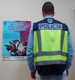 Un agente ante el cartel de la campaña contra la trata de mujeres