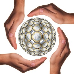 Varias manos rodeando una bola de monedas de un euro