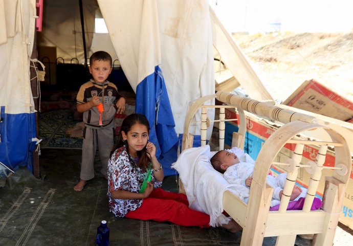Children fleeing violence in the Iraqi city of Mosul, sit in front of a tent at 