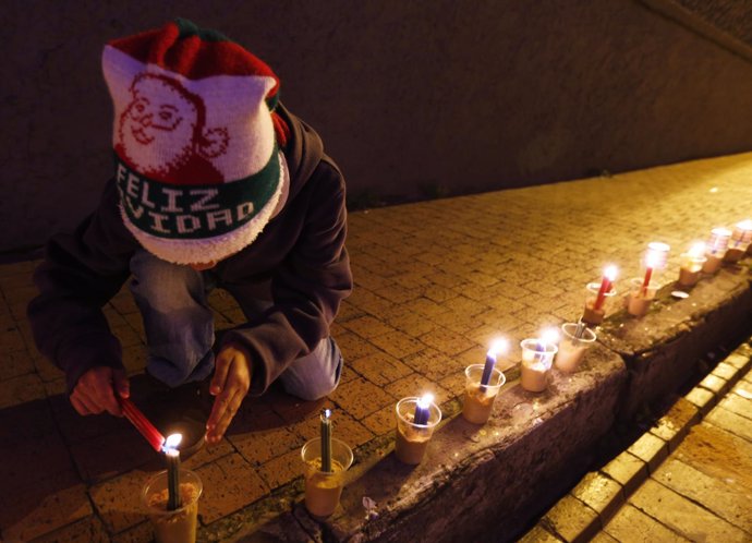 A boy lights candles during Little Candles' Day in Bogota