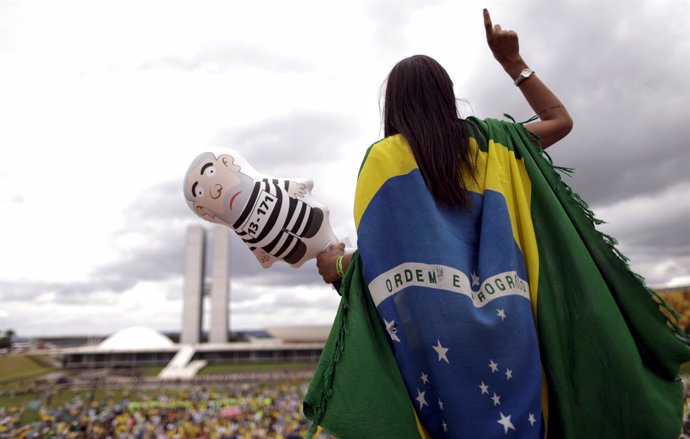 A demonstrator gestures as she holds an inflatable doll of Brazil's former presi