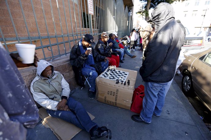 Two people play a game of chess as they wait in line for an early Thanksgiving m