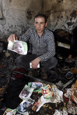 Un pariente del bebé palestino muerto muestra un retrato del bebé