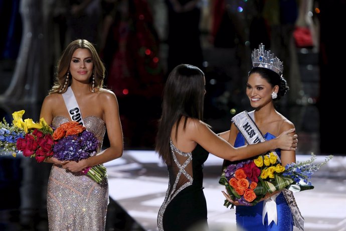 Miss Colombia Gutierrez stands by as Miss Universe 2014 places the sash on Miss 