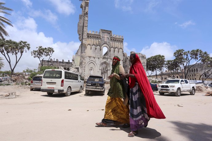 Mujeres somalíes caminan delante de restos de catedral de Mogadiscio