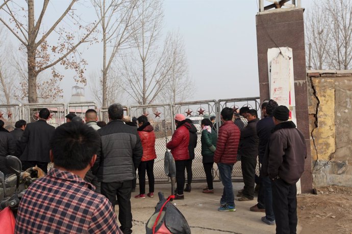 People stand outside a gypsum mine after it collapsed on Friday morning, in Ping