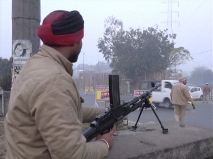 A policeman stands guard with a gun as vehicles pass by, following an attack on 