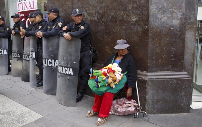 Street vendor Laura Chikasaka Mamani sells puppets next to Peruvian anti-riot po