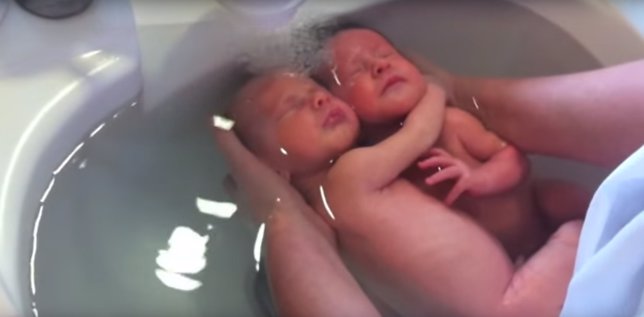 Mellizos recién nacidos se abrazan durante un baño