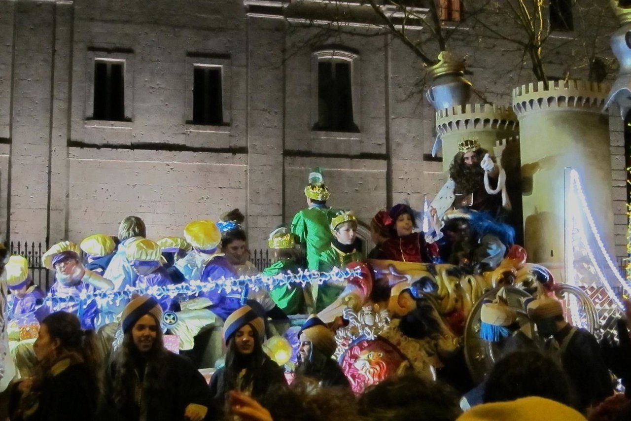 El rey Gaspar lanza caramelos desde su carroza acompañado por sus pajes
