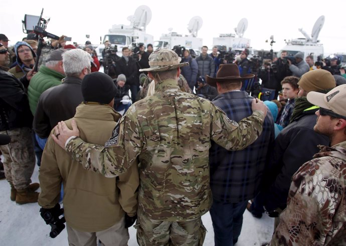 Militiamen embrace along with Ammon Bundy, after Bundy spoke to the media at the
