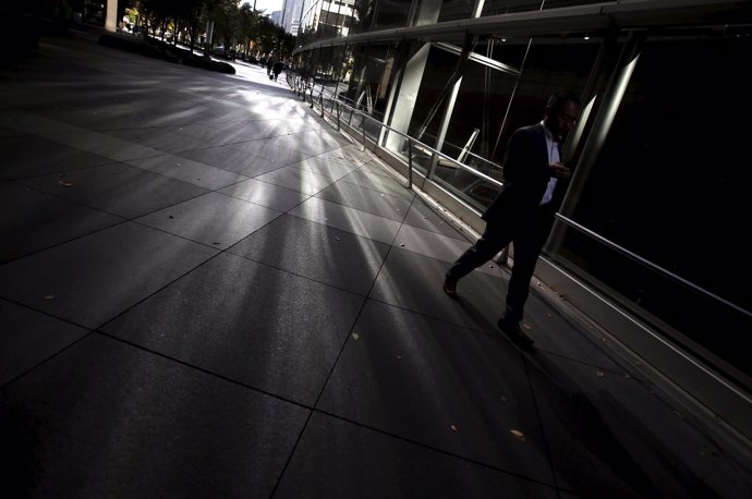 A man holding his mobile phone walks a street at a business district in Tokyo