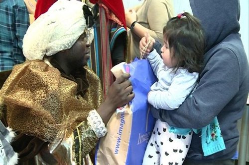 El rey Baltasar hace entrega de un regalo a una niña.
