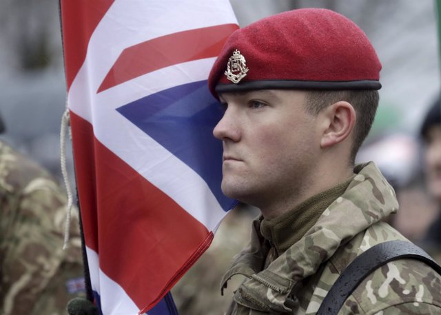 British Army soldier stands near his national flag during Latvia's Independence 