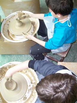 Dos escolares moldeando sus piezas de cerámica en el Taller Escuela de Muel