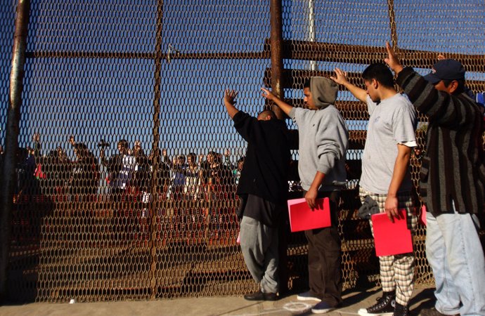 Un grupo de deportados en la valla que separa San Diego de Tijuana