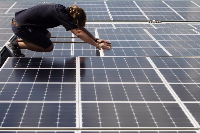 Worker moves solar panels on the deck of the world's largest solar-powered boat 