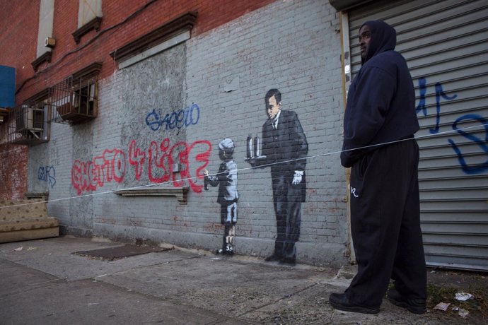 A man guards a graffiti by British street artist Banksy in the Bronx section of 
