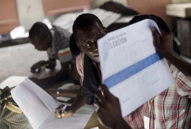 An electoral worker holds up a ballot for scrutiny during vote counting in Port-