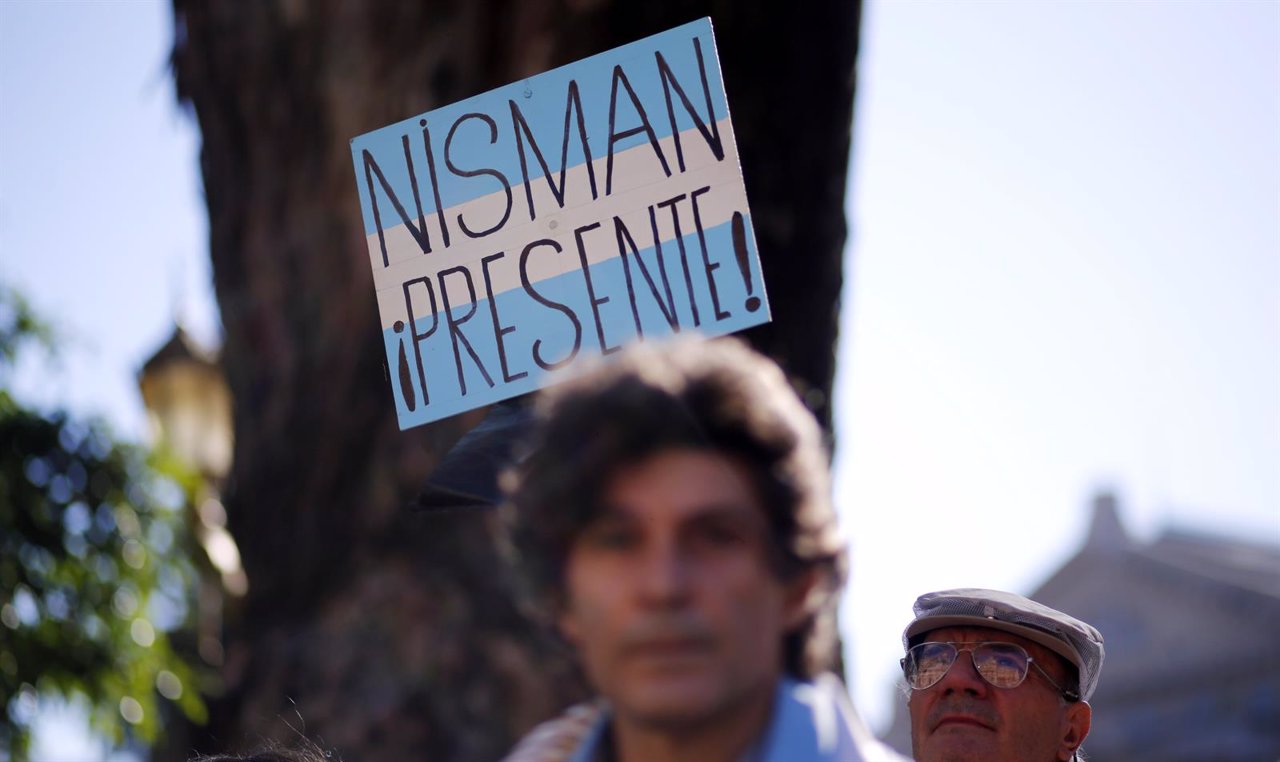 Un hombre sostiene un cartel que dice " Nisman presente "