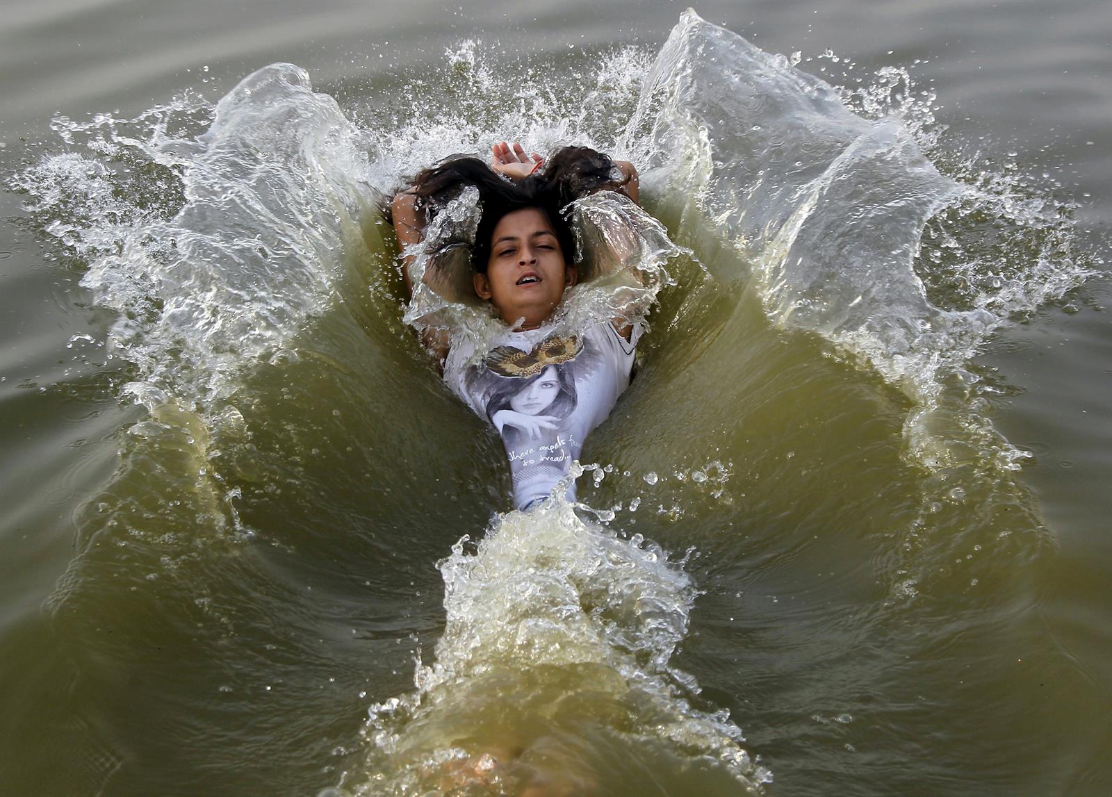 Una chica se refresca en el río Ganges, en India