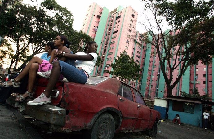 Girls sit on an old car at the "Pinto Salinas" neighborhood during a hip-hop per