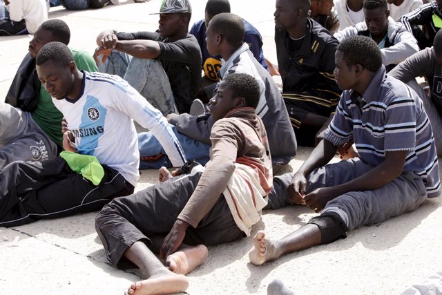 Illegal migrants sit after they were detained at the Libyan naval base in the co