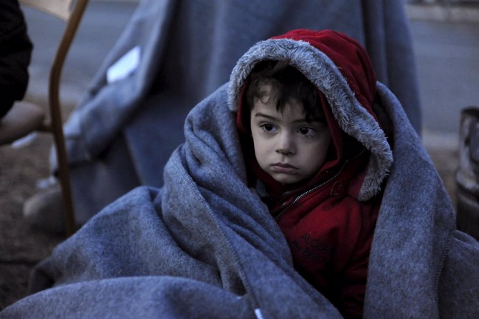 Un niño migrante cubierto con una manta cerca del pueblo griego de Idomeni