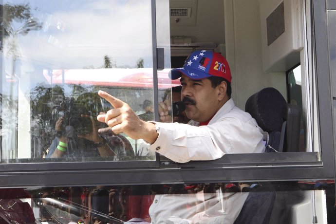 Venezuela's President Nicolas Maduro drives a bus as he talks during the launch 