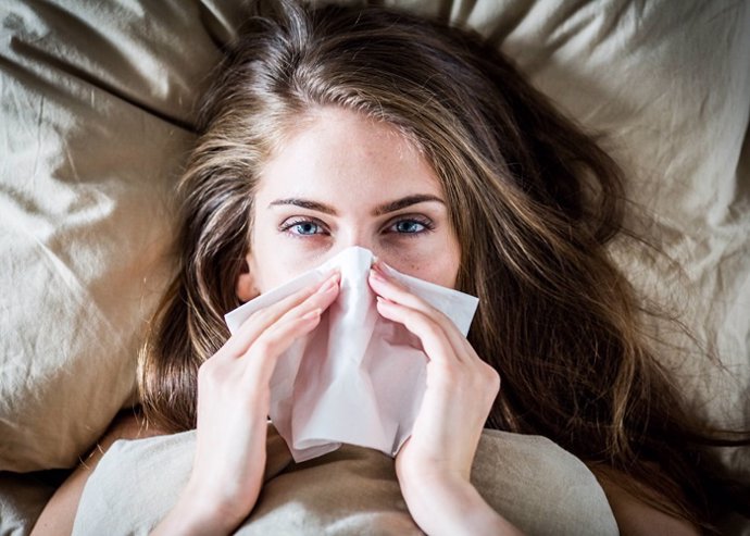 Woman with a cold using tissue.