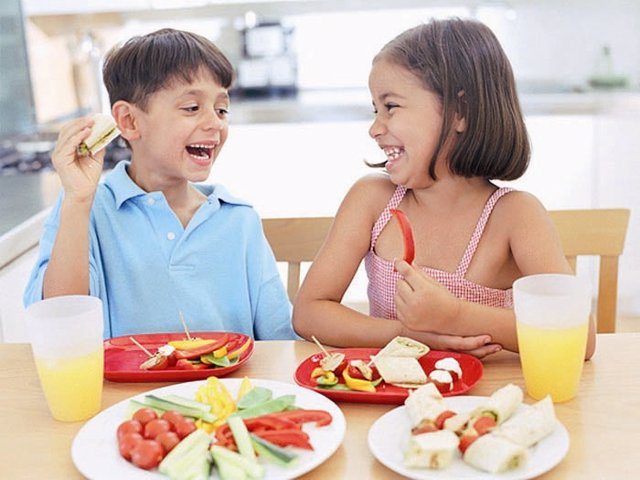 Niños comiendo frutas y verduras