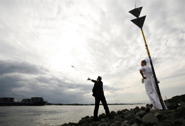 Una pareja d enovios lanzan un botella al mar con un mensaje dentro