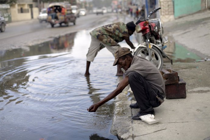 Un hombre se lava y bebe agua de un charco en Haití