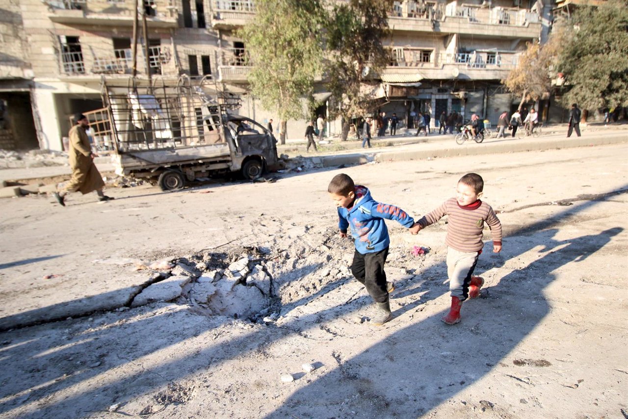 Niños jugando junto a los restos de un bombardeo en Alepo
