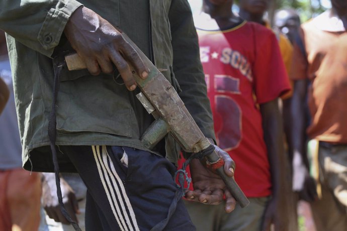 Un miliciano anti-balaka sostiene un arma frente a antiguos niños soldado