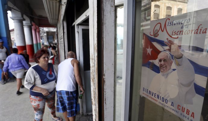 Cubans walk near a photograph of Pope Francis with the message in Spanish that r