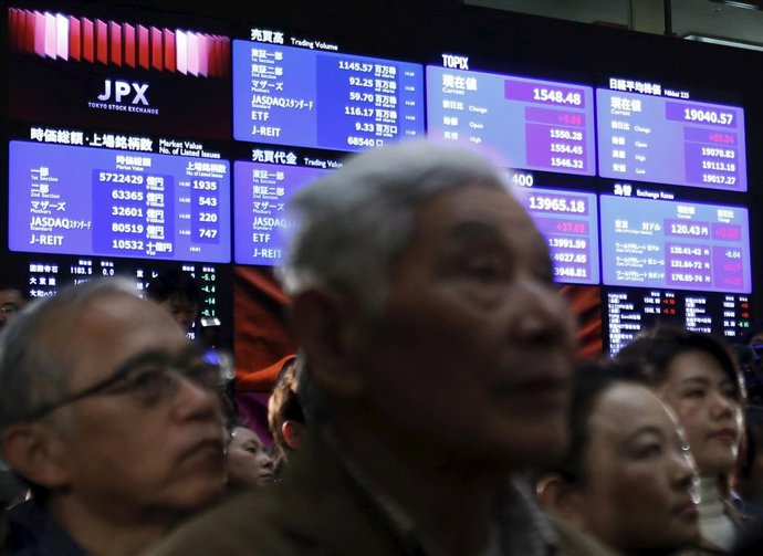 A stock quotation board displaying Japan's Nikkei average is seen behind visitor