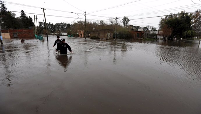 Two men cross a flooded street in Lujan